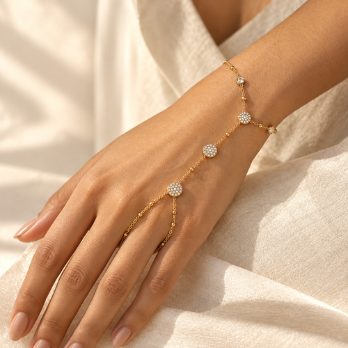 Amora gold-tone heart hand chain featuring pavé crystal heart motifs, polished gold heart charms, a delicate linked chain, and a sparkling finger-loop accent by INDAAH.