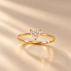Celeste Heart Ring by INDAAH featuring a clear heart-shaped stone in a delicate gold-tone band with a three-prong setting.