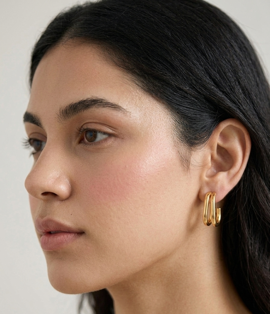 Pair of high-polish gold double-band tubular open oval hoop earrings with post backs on a white background.