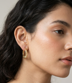 Pair of polished gold oval hoop earrings featuring a scalloped outer rim and a central heart motif on a white studio background.