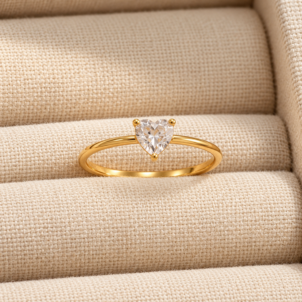 Celeste Heart Ring by INDAAH featuring a clear heart-shaped stone in a delicate gold-tone band with a three-prong setting.