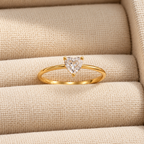 Celeste Heart Ring by INDAAH featuring a clear heart-shaped stone in a delicate gold-tone band with a three-prong setting.