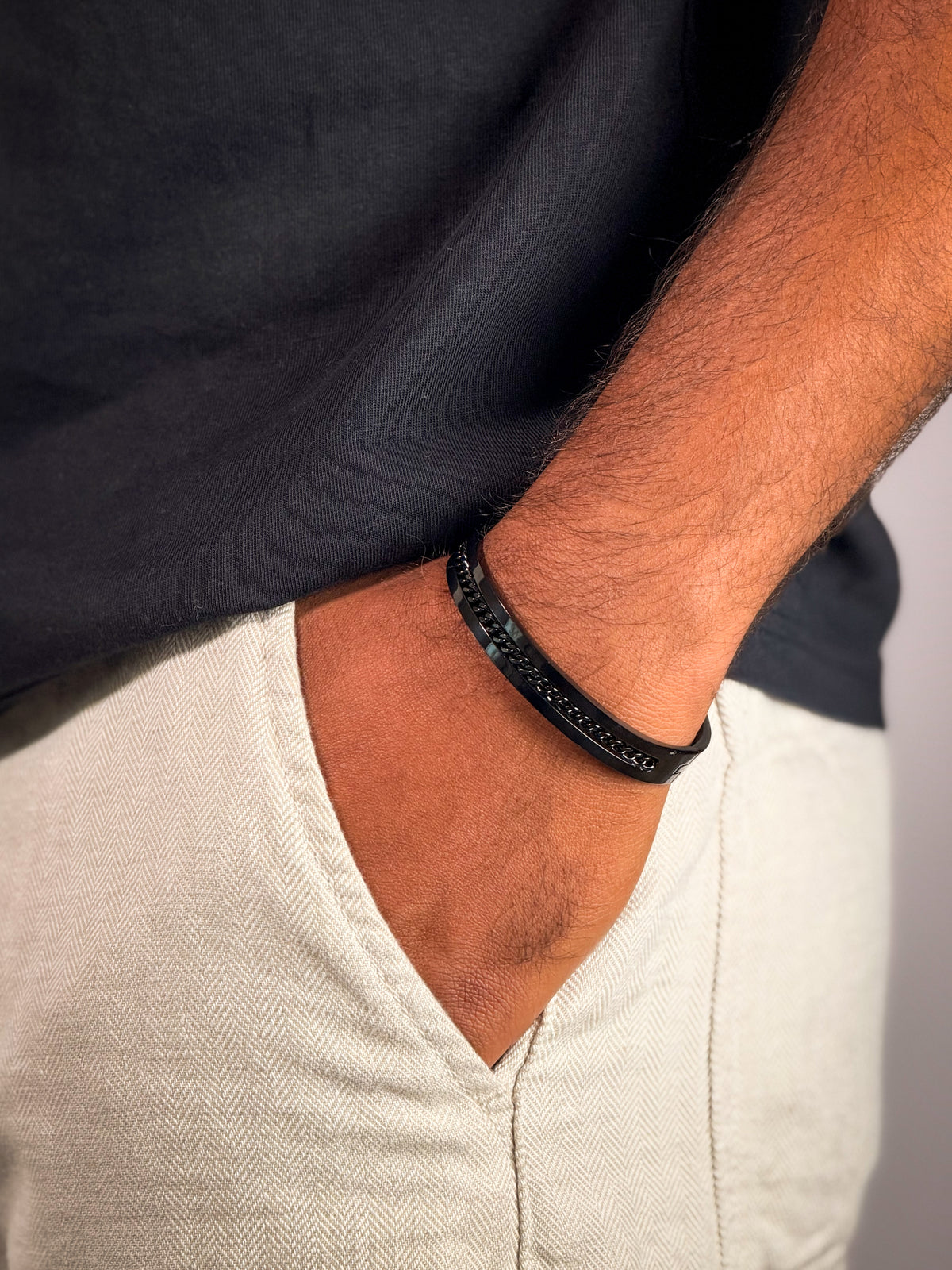Model wearing Dark industrial-finish kada bracelet with link detailing for men.