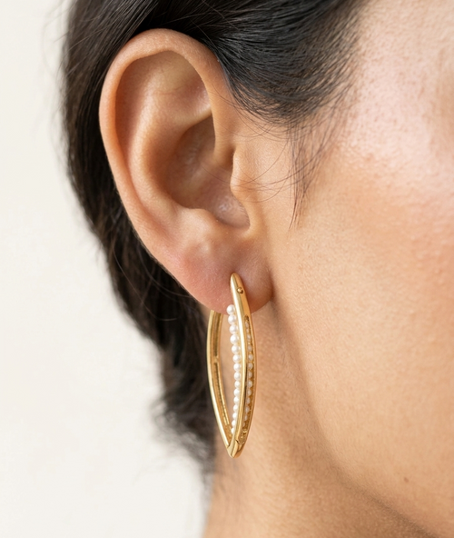 Model wearing Marquise-shaped gold-plated hoop earrings with pearl accents.