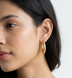Model wearing Tapered teardrop-shaped gold-plated hoop earrings.