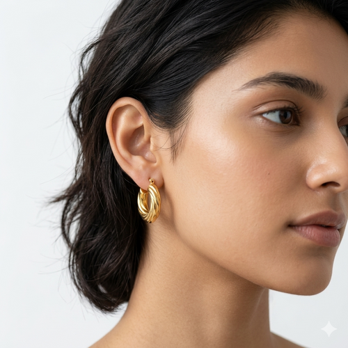 Model wearing Twisted croissant-style gold-plated hoop earrings.