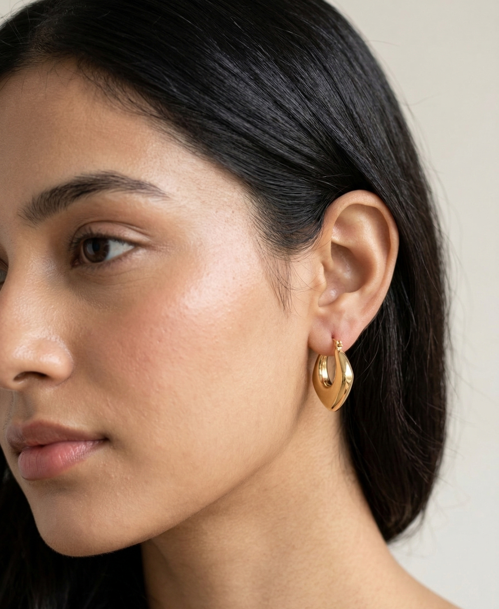 Model wearing Sculpted gold-plated hoop earrings with a diamond-textured design.