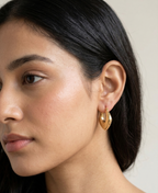 Model wearing Sculpted gold-plated hoop earrings with a diamond-textured design.